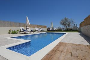 uma piscina com um deque e cadeiras de madeira em Arismari Villa - Heated Private Pool em episkopi-heraklion