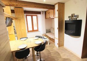 a small room with a table and chairs and a television at Charmant Studio Cité Vauban in Briançon