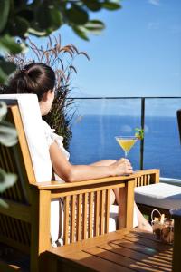 
a woman sitting on a bench looking at the ocean at Madeira Regency Cliff - Adults Only in Funchal
