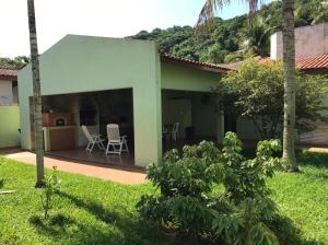 une maison verte avec une terrasse dans la cour dans l'établissement Casa a 50 metros da Praia da Riviera no Jardim São Lourenço - Casa com Wi-Fi, à Bertioga