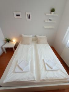 ein großes weißes Bett mit weißer Bettwäsche und Kissen in der Unterkunft Budapest Airport Apartment in Budapest