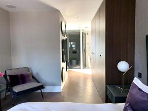 a bedroom with a bed and a chair and a hallway at Soho Boutique apartments in London