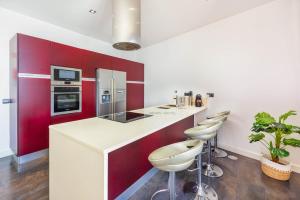 een keuken met rode en witte kasten en krukken bij Villa Amplitude in Câmara de Lobos
