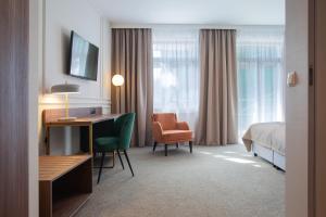 a hotel room with a bed and a desk and a chair at Hotel Willa Tatrzańska in Krynica Zdrój
