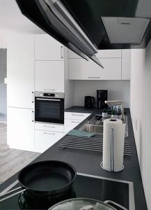 a kitchen with white cabinets and a black frying pan on a counter at Fuchsbau in Baiersbronn