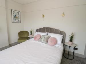 a bedroom with a white bed with pink pillows at Monarfon in Amlwch