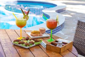 a table with two drinks and a tray of food at Hotel Pousada Imbassai in Imbassai