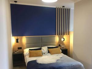a bedroom with a large bed with a blue wall at Koralia Domki i Apartamenty in Sarbinowo