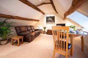 a living room with a leather couch and a table at Neroli River View Apartment in Bourton on the Water