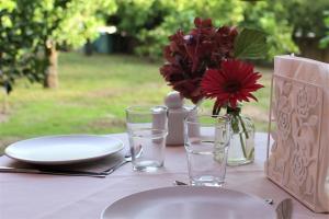 einen Tisch mit Tellern und Gläsern und eine Vase mit Blumen in der Unterkunft Il giardino degli aranci in Modolo