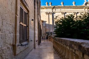 an alley in an old building with a window at The Xara Palace Relais & Chateaux in Mdina