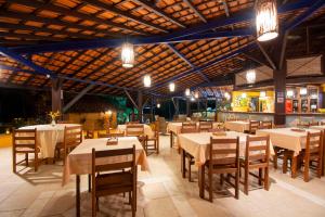 een eetkamer met tafels, stoelen en verlichting bij Hotel Pousada Imbassai in Imbassai