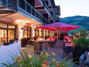 een restaurant met tafels en stoelen en een roze parasol bij Hotel Adapura Wagrain in Wagrain