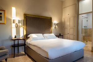 a bedroom with a large white bed and a bathroom at The Xara Palace Relais & Chateaux in Mdina