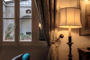 a lamp sitting next to a window with a curtain at The Xara Palace Relais & Chateaux in Mdina