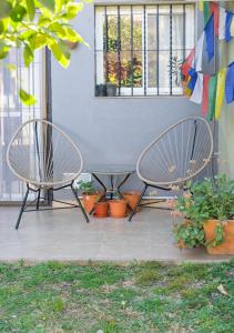 zwei Stühle und Topfpflanzen vor einem Fenster in der Unterkunft Casa con pileta Aeropuerto Circunvalación Kempes Quorum Siglo 21 in Cordoba