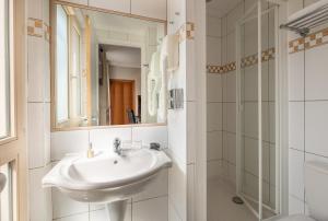 a white sink sitting under a mirror in a bathroom at Hotel London in Paris