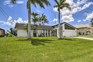 a house with palm trees in front of it at Canal-Front Cape Coral Home: Pool & Patio in Cape Coral