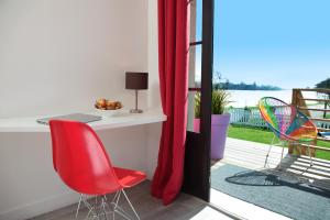 a red chair and a desk on a balcony at Les Canisses in Saint-Pierre-la-Garenne