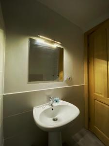 La salle de bains est pourvue d'un lavabo blanc et d'un miroir. dans l'établissement Beko’s garden Inn, à Mestia