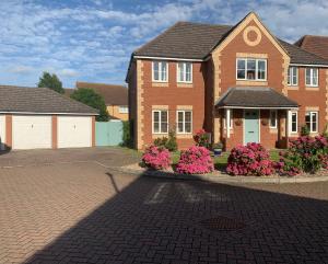 a brick house with pink flowers in a driveway at Willow Farm Way in Herne Bay