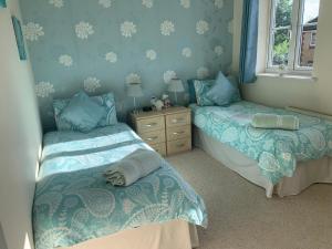 two beds in a room with blue walls at Willow Farm Way in Herne Bay