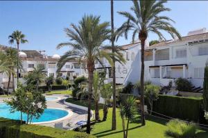 een uitzicht op een resort met palmbomen en een zwembad bij Apartamento en Urbanización Mezquida Javea recién reformado in Jávea