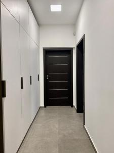 pasillo con puerta negra y armarios blancos en Jogász Street - A. Apartman, en Pécs