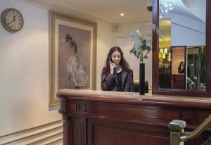 Kobieta rozmawiająca przez komórkę za ladą w obiekcie Hotel London w Paryżu