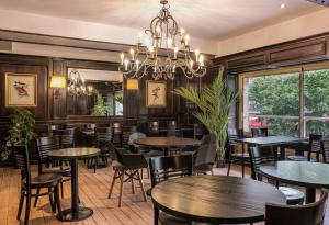 een restaurant met tafels en stoelen en een kroonluchter bij Hotel London in Parijs