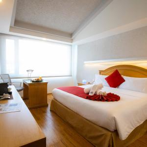 1 dormitorio con 1 cama grande con almohadas rojas en Hotel Horizon & Convention Center en Morelia