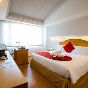 a bedroom with a large bed with red pillows at Hotel Horizon & Convention Center in Morelia