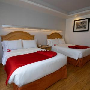a hotel room with two beds with red sheets at Hotel Horizon & Convention Center in Morelia