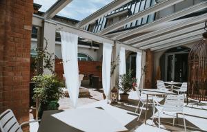 eine Terrasse mit weißen Stühlen und Tischen sowie ein Gebäude in der Unterkunft Hotel Cavallo Bianco in Reggiolo