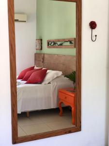 a mirror reflecting a bedroom with a bed with red pillows at Pousada Tatuapara in Praia do Forte