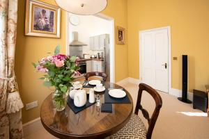 a dining room table with a vase of flowers on it at Arkle - Five Star Town Centre Apartment, Cheltenham in Cheltenham