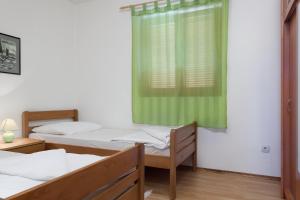 duas camas num quarto com uma cortina verde em Manda em Karlobag