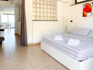 um quarto com uma cama branca e piso em madeira em Giardini Beach loft em Giardini Naxos