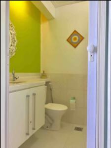 a bathroom with a toilet and a green wall at Ilha Porchat - Loft Vista Incrível in São Vicente