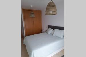 - une chambre avec un lit blanc et deux lampes suspendues dans l'établissement Apartamento Aurora llanes 4 pax, à Posada de Llanes