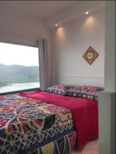 a bedroom with a bed and a large window at Ilha Porchat - Loft Vista Incrível in São Vicente
