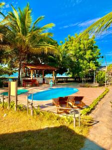 uma piscina com mesas e cadeiras e uma palmeira em Pousada Sol Dourado em Jiloca de Jericoacoara