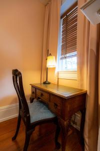 a desk with a lamp and a chair next to a window at Thomas Rose Inn in Lewisburg