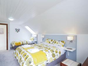a bedroom with a large bed with yellow and white sheets at Cottage 382 - Recess in Ballynahinch