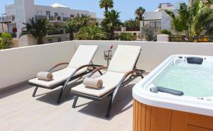 three chairs and a hot tub on a balcony at Vitalclass Lanzarote Resort in Costa Teguise