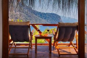 two chairs and a table with a glass of wine on a porch at La Boheme Kabak Adults Only in Faralya
