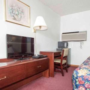 Habitación de hotel con escritorio, TV y cama en Oak Grove Inn, en Oak Grove