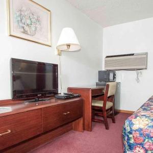 una camera d'albergo con scrivania, TV e letto di Oak Grove Inn a Oak Grove