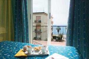 taca z ciastkami i kubkami na stole z oknem w obiekcie Hotel Elisabetta w mieście Sestri Levante