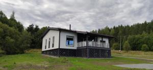 a small white house with a porch on a field at Cottage Village Moklakhti in Kortela